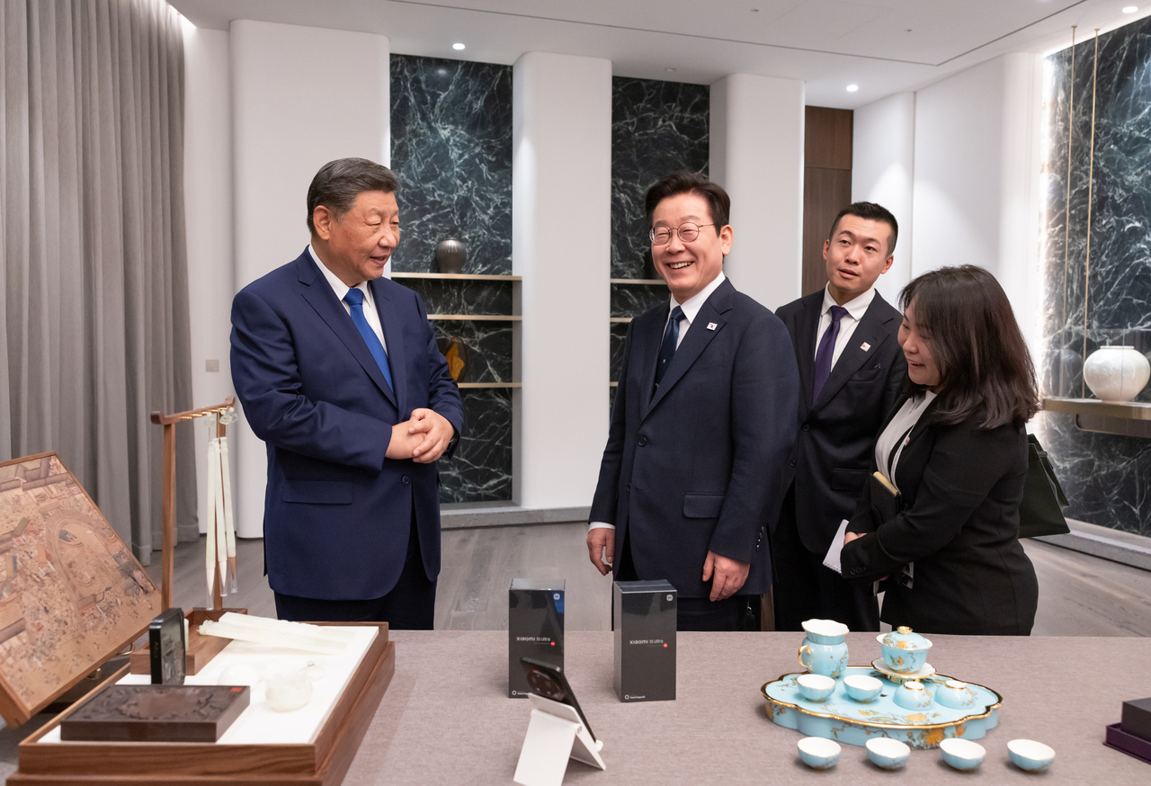 President Lee Jae Myung (left) and President Xi Jinping look at gifts prepared for each other at Sono Calm Hotel in North Gyeongsang Province on Saturday. (Yonhap)