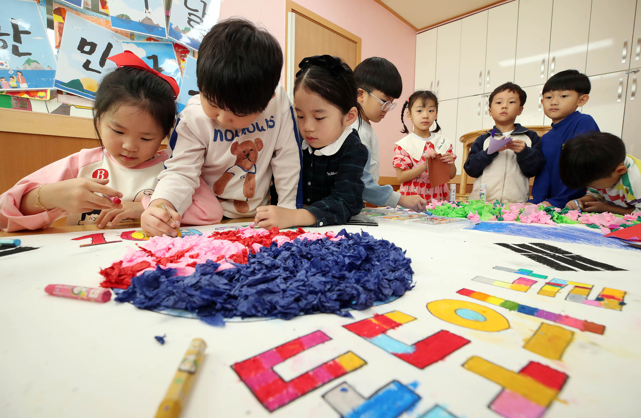 Children make an art project in the shape of the Korean national flag in this file photo taken on Oct. 23 at a daycare center in Gwangju. (Yonhap)