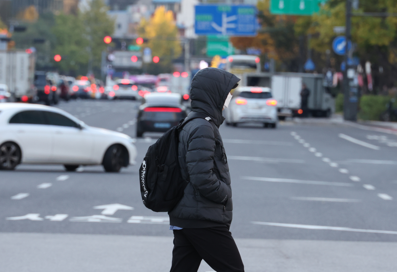 A pedestrian dressed in a thick, padded jacket crosses the street in Seoul on Monday morning, the same day a cold wave advisory was issued for the capital city. (Yonhap)