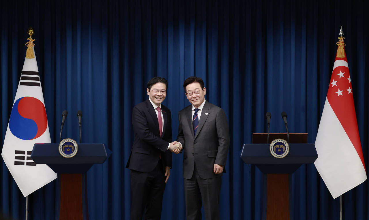 President Lee Jae Myung and Singaporean Prime Minister Lawrence Wong shake hands during a joint press conference on Sunday at the presidential office in Seoul. (Yonhap)