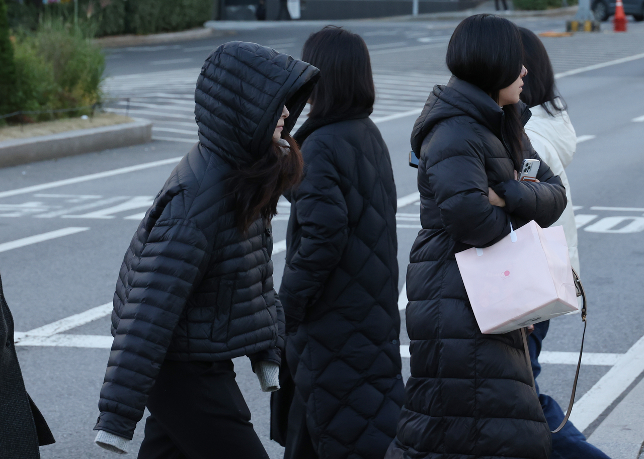 Commuters dressed in winter attire head to work in Seoul on Monday as temperatures dipped below freezing. (Yonhap)