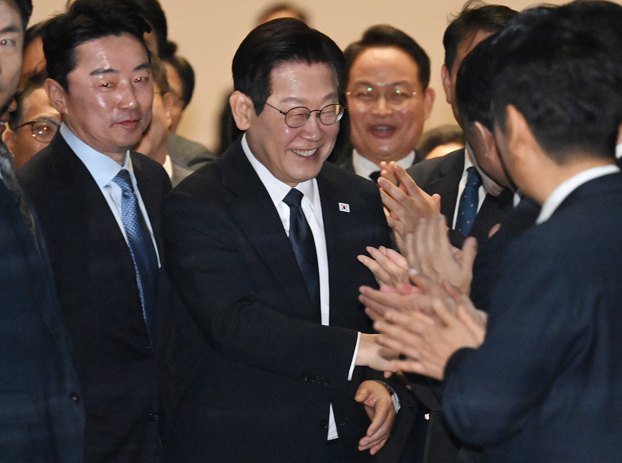 President Lee Jae Myung shakes hands with ruling party lawmakers after delivering a policy speech on next year’s government budget at the National Assembly in Yeouido, Seoul, on Tuesday. (Yonhap)