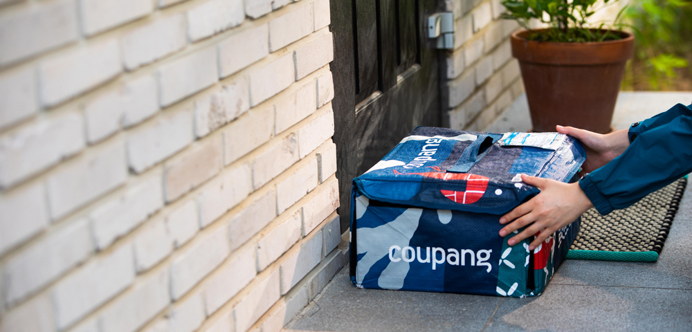 A Coupang delivery worker places a reusable insulated Fresh Bag on a customer’s doorstep in the early morning. Exclusive to "Coupang Wow" members, the bag keeps cold groceries fresh until retrieved and is collected with the next order, as part of a system that offers unlimited pre-dawn delivery for fresh goods over 15,000 won, all for a monthly membership fee of 7,890 won a month. It also includes unlimited overnight delivery of other daily essentials and products with no minimum spend. (Coupang)