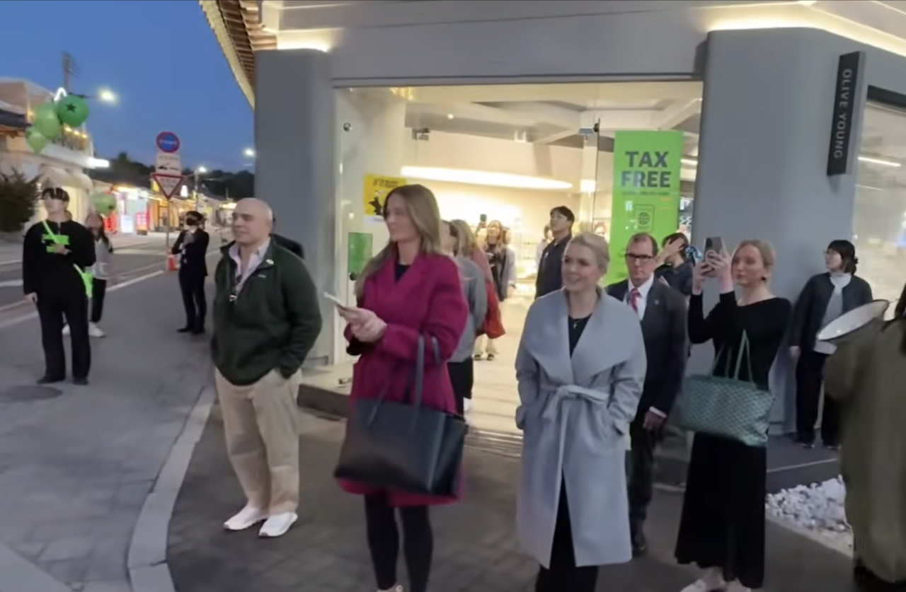 Leavitt (center right) and Martin outside Olive Young Hwangnam branch, watching a rally welcoming Trump passing by. (YouTube livestream)