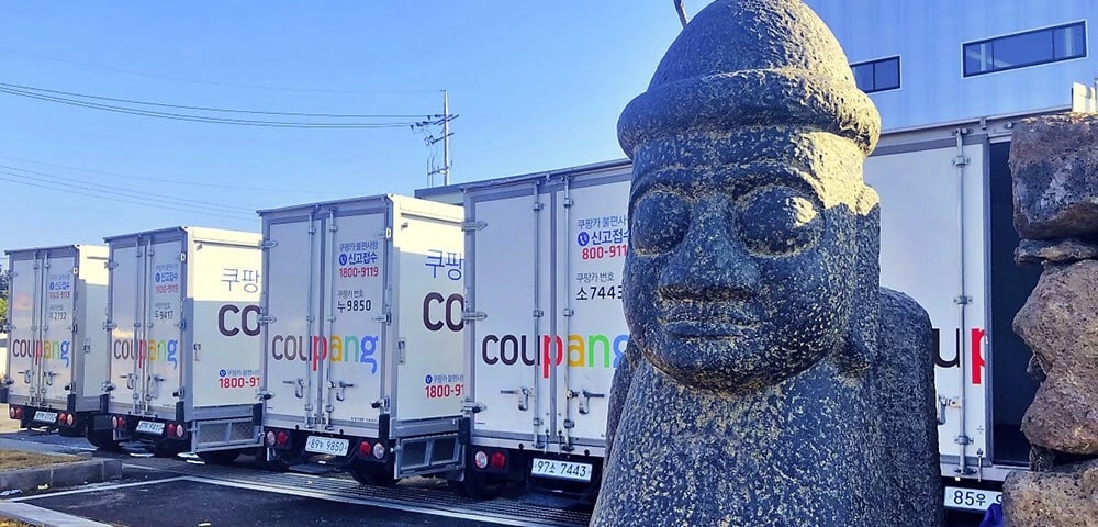 Coupang delivery trucks are lined up at a logistics site in Jeju, where the company began offering overnight fresh‑food delivery for the first time on the island starting February this year. (Coupang)