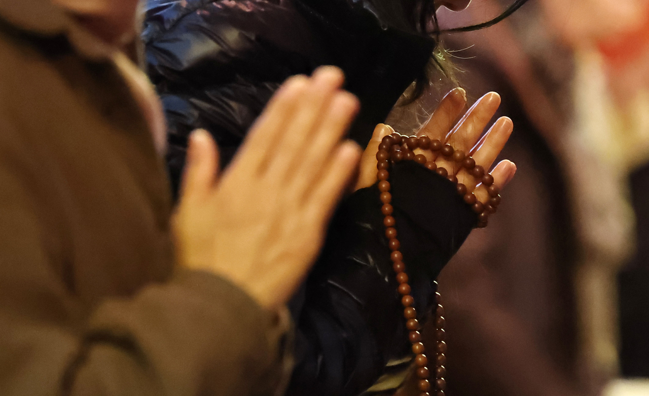 Parents pray for their test-taking children on Monday at Jogyesa in Seoul. (Yonhap)