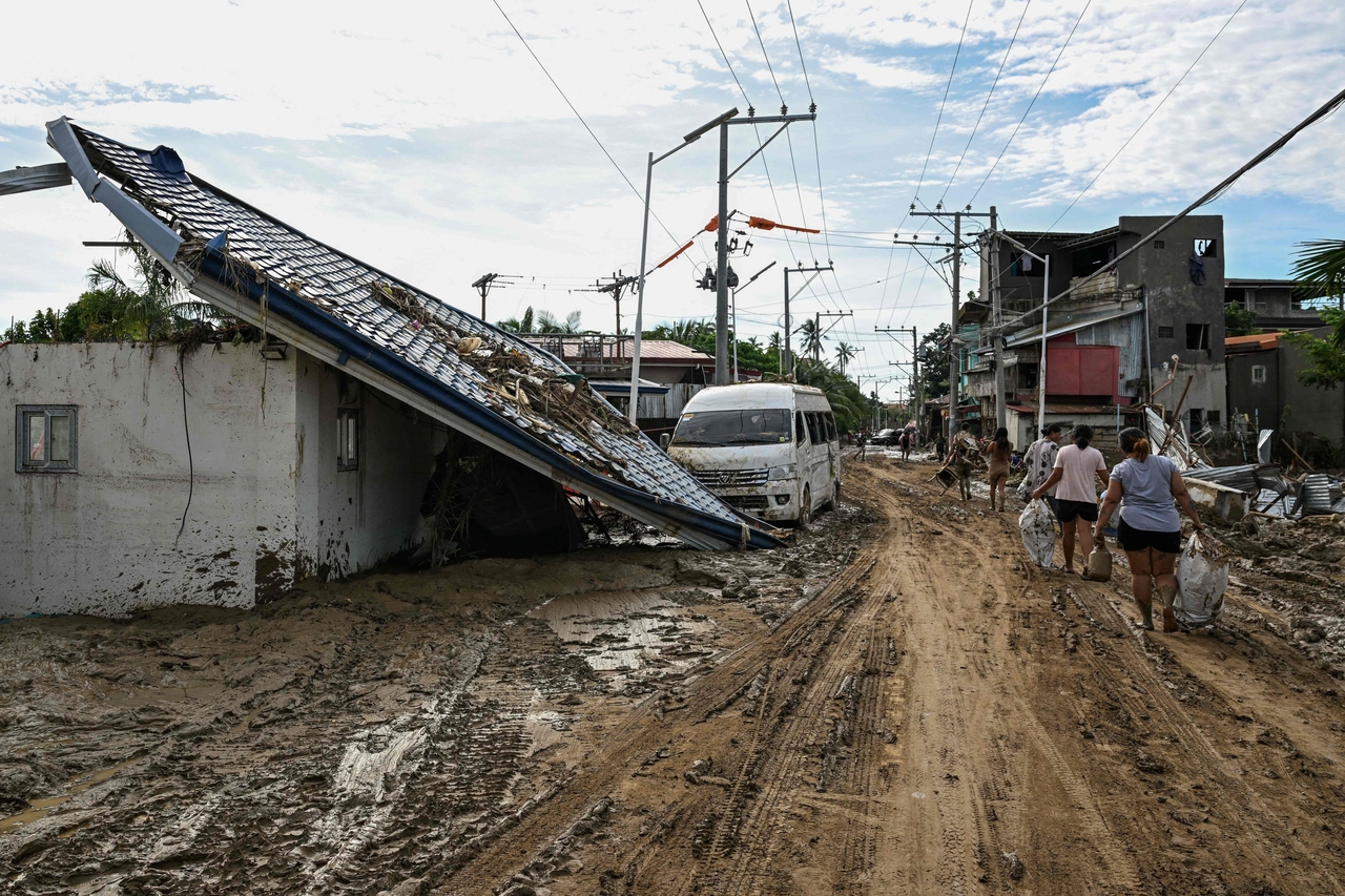 Residents walk along a mud covered street in the aftermath of Typhoon Kalmaegi in Liloan, Cebu, Thursday. (AFP-Yonhap)