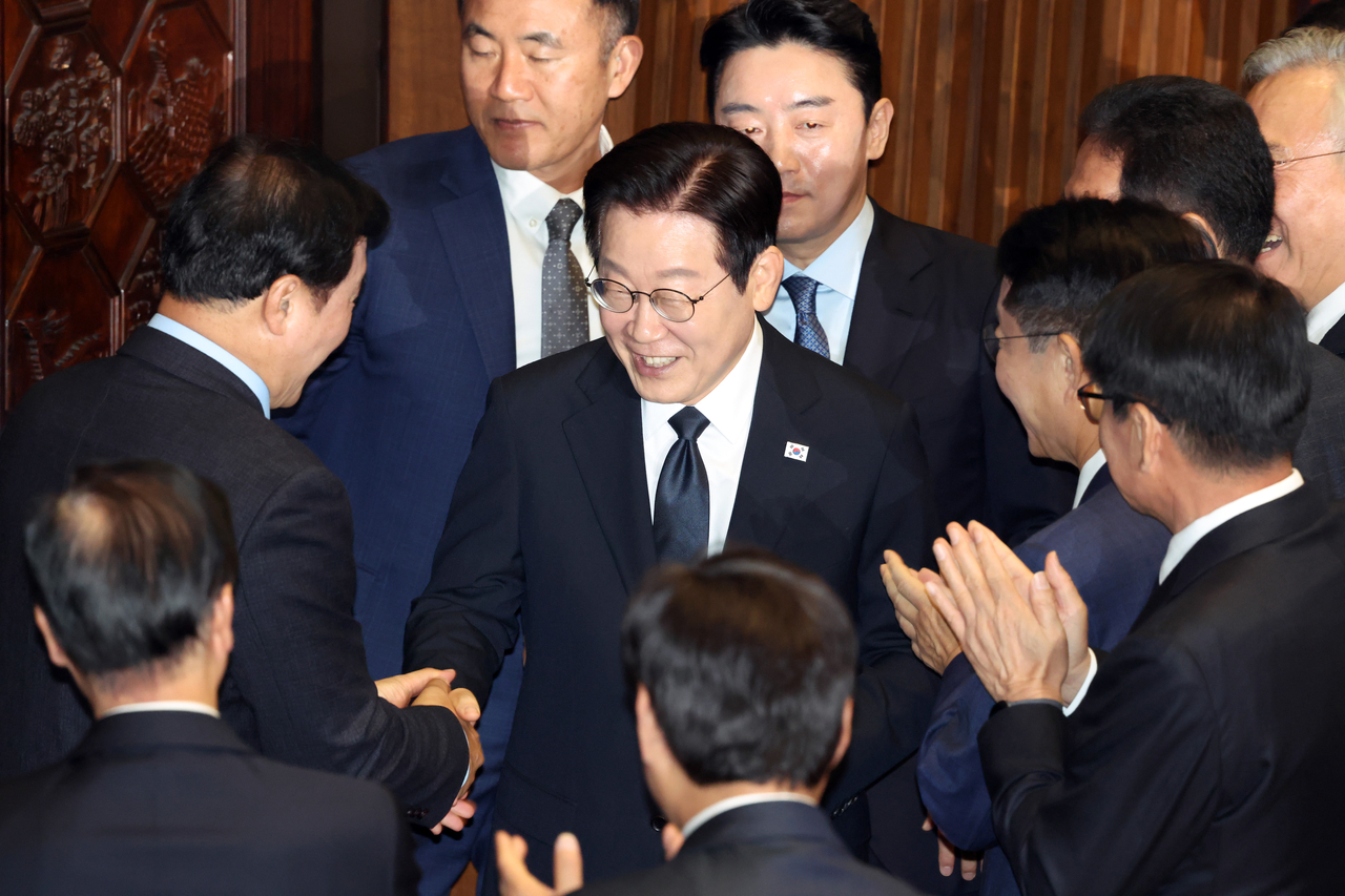 President Lee Jae Myung (center) shakes hands with lawmakers after delivering his policy speech on the 2026 budget plan at the National Assembly in Seoul on Tuesday. (Newsis)
