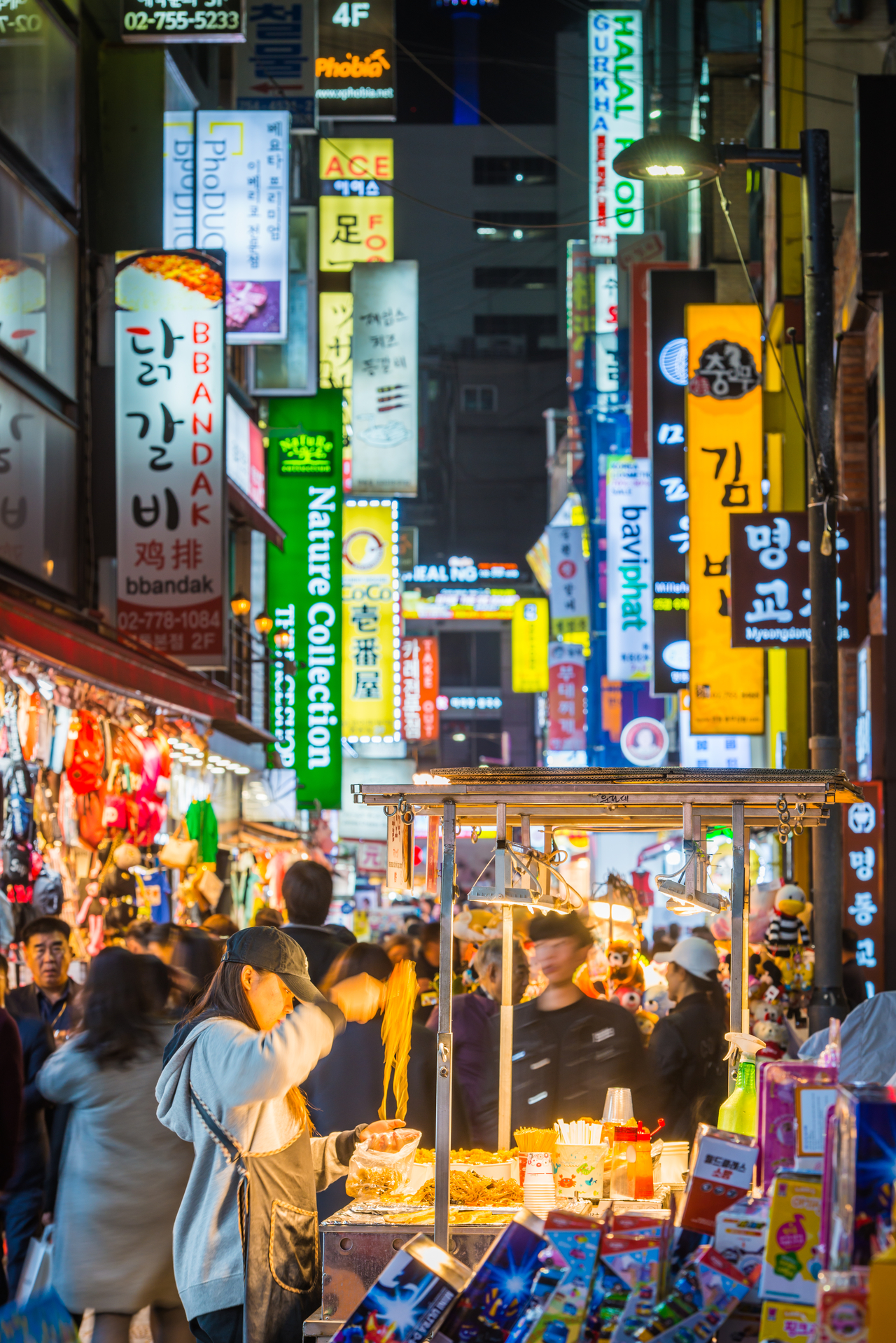 Woman preparing noodles at a food stall at night in the busy Myeongdong shopping district of central Seoul, South Korea. (Getty Images Bank)