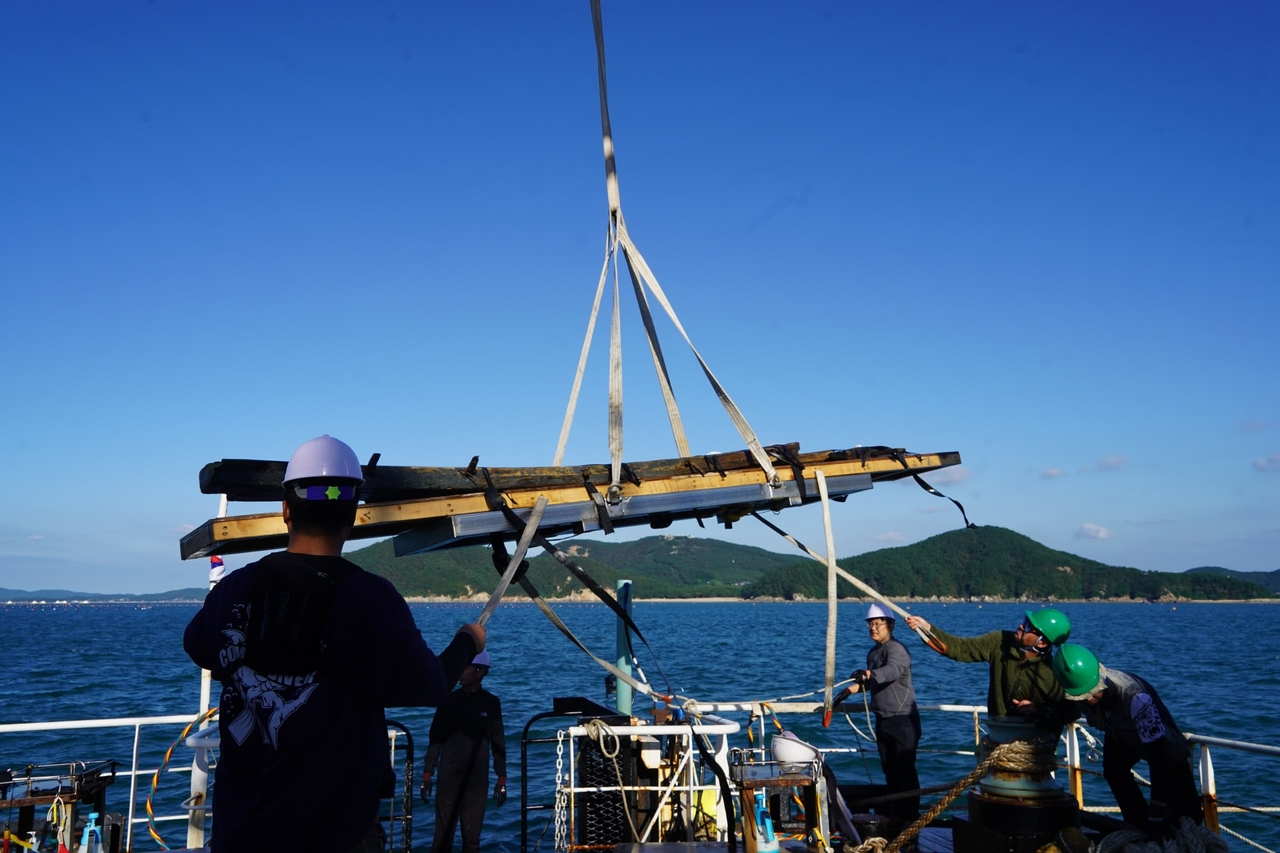 A team hoists part of Mado 4’s wooden frame during its October recovery off Korea’s west coast, the country’s first complete excavation of a Joseon-era ship. (Yonhap)