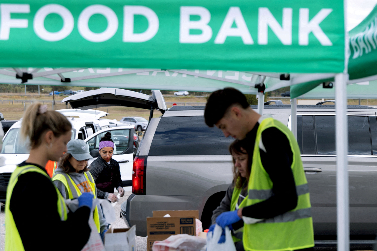 Volunteers place food items in vehicles during a mobile food distribution at Cedar Creek High School in Cedar Creek, Texas, Nov. 1.   Reuters-Yonhap