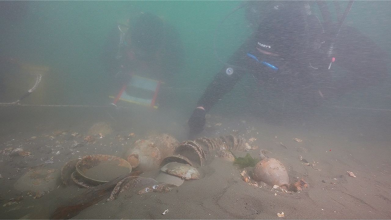 Marine archaeologists inspect a stack of celadon pottery partially buried in sediment at the suspected site of a 12th-century shipwreck off Korea’s west coast. (Yonhap)