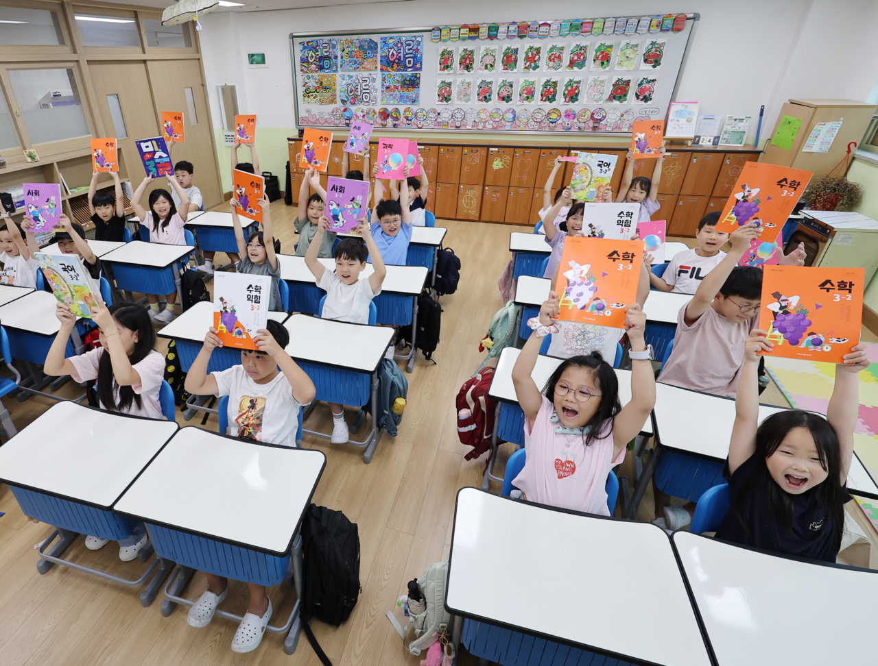 Students hold up their textbooks in a third-grade classroom at Maesan Elementary School in Suwon, Gyeonggi Province, Sept. 20. (Yonhap)