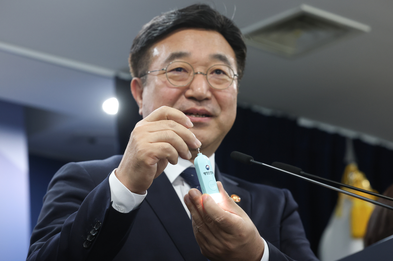 Interior Minister Yun Ho-jung activates a personal safety alarm the government plans to distribute to students during a joint briefing on comprehensive measures to protect children on their way to and from school, at Government Complex Seoul on Tuesday. (Yonhap)