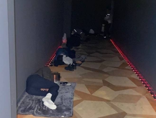 Police officers deployed for the APEC 2025 summit in Gyeongju sleep in a dark hallway due to a shortage of accommodations, with some reportedly resting on cinema floors or near screens during overnight shifts. (National Police Union)