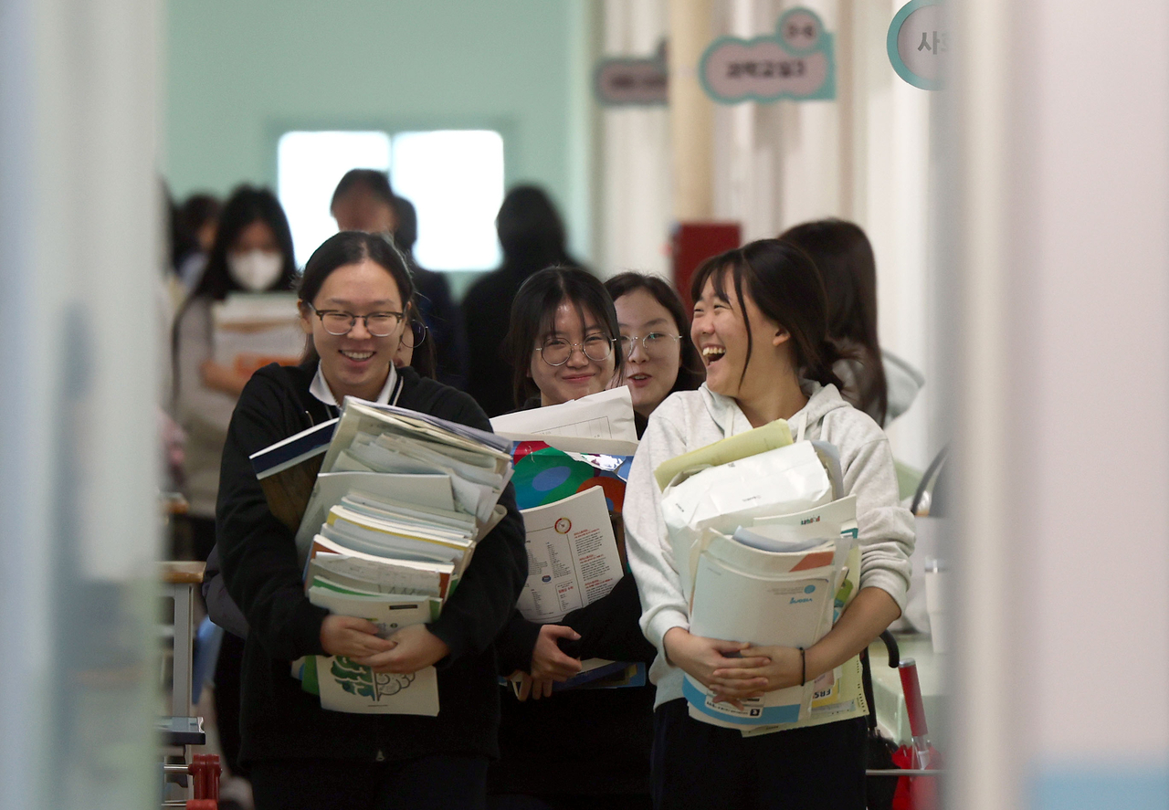 Just three days before the 2026 Suneung, third-year students at Seongji Girls’ High School in Changwon, South Gyeongsang Province, carry their test prep books. (Yonhap)
