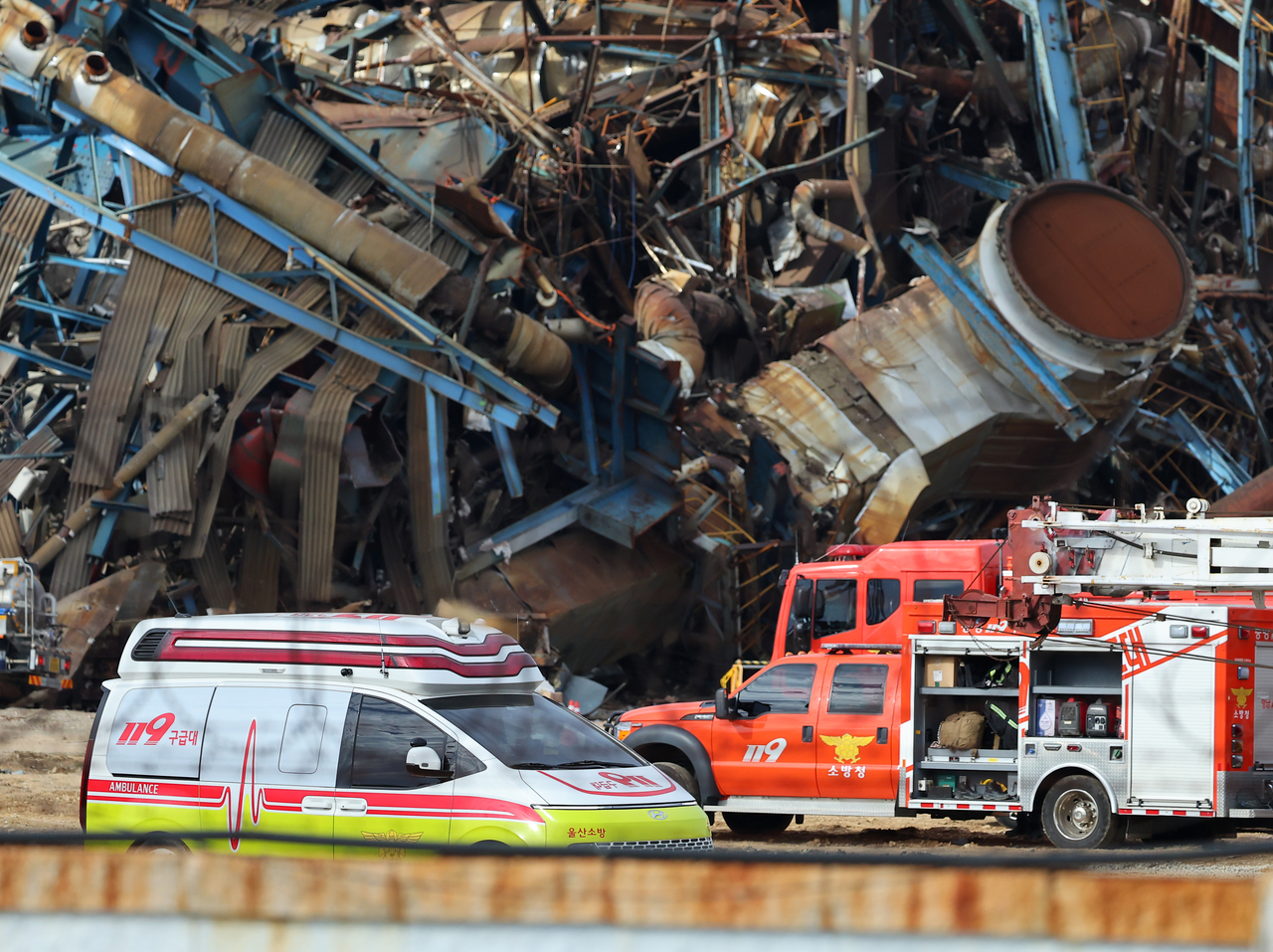 Rescue vehicles pass near the collapsed boiler tower at the Korea East-West Power Co. site in Ulsan on Wednesday. Of the seven people buried in the incident, five have been found and confirmed dead, while two workers remain trapped under the debris. (Yonhap)