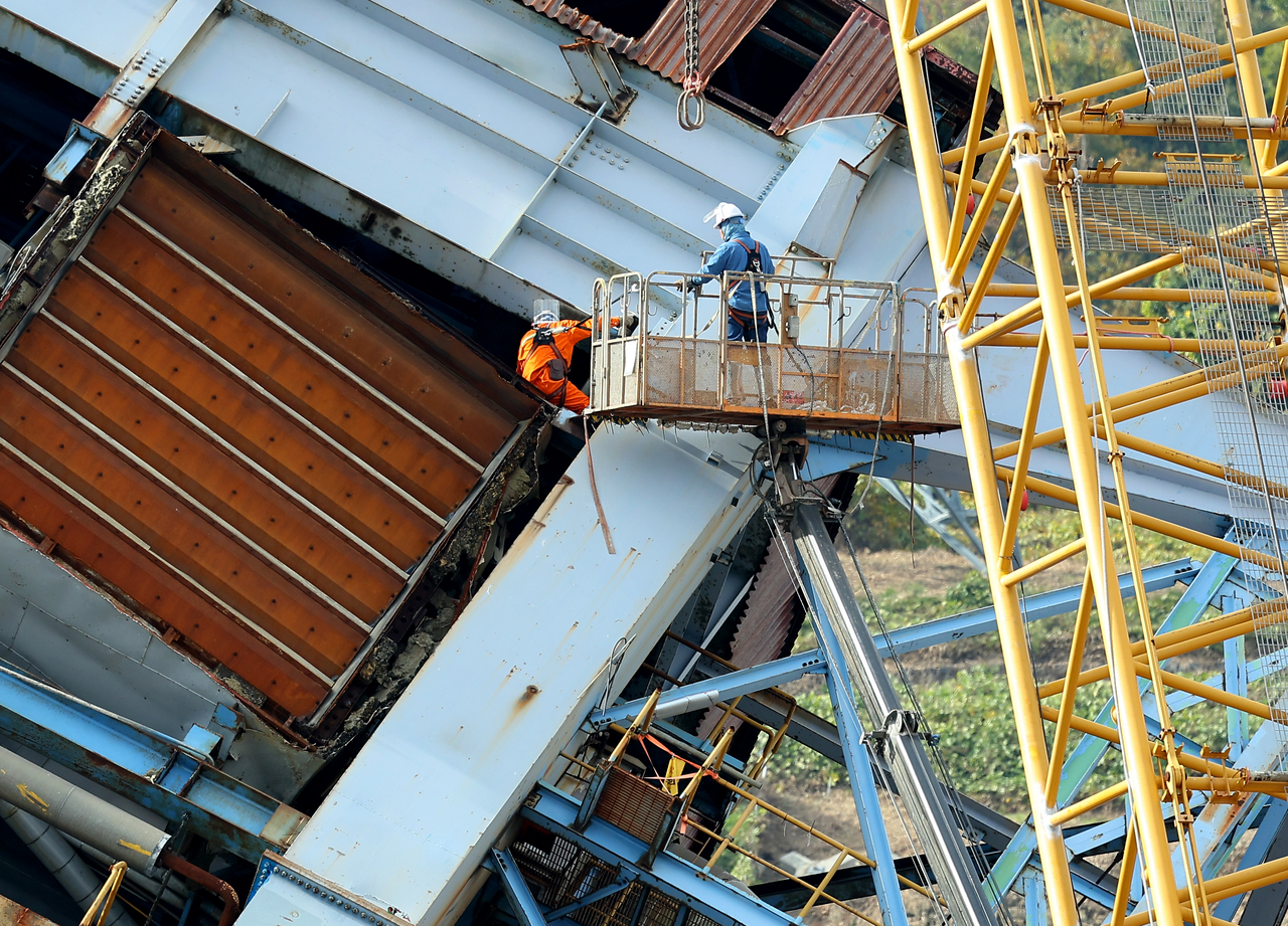 Workers secure the upper part of the structure with a crane to prevent further collapse at the Korea East-West Power Co. site in Ulsan, on Wednesday.  (Yonhap)