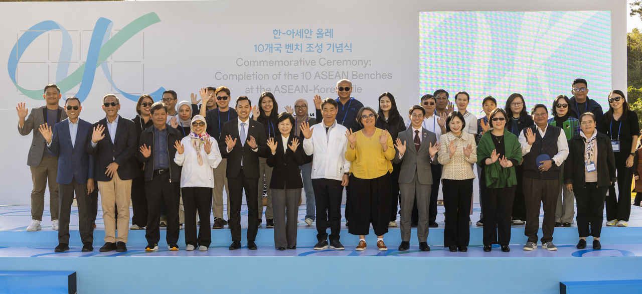 ASEAN-Korea Centre Secretary-General Kim Jae-shin (seventh from left) poses for a group photo with ASEAN ambassadors in Korea, Jeju Special Self-Governing Province Vice Gov. Kim Ae-sook (sixth from left), Jeju Olle Foundation CEO Ahn Eun-joo (eighth from left), and ASEAN journalists, at the completion ceremony for the ASEAN Ollegil benches, at Parnas Hotel Jeju on Tuesday. (The ASEAN-Korea Centre)