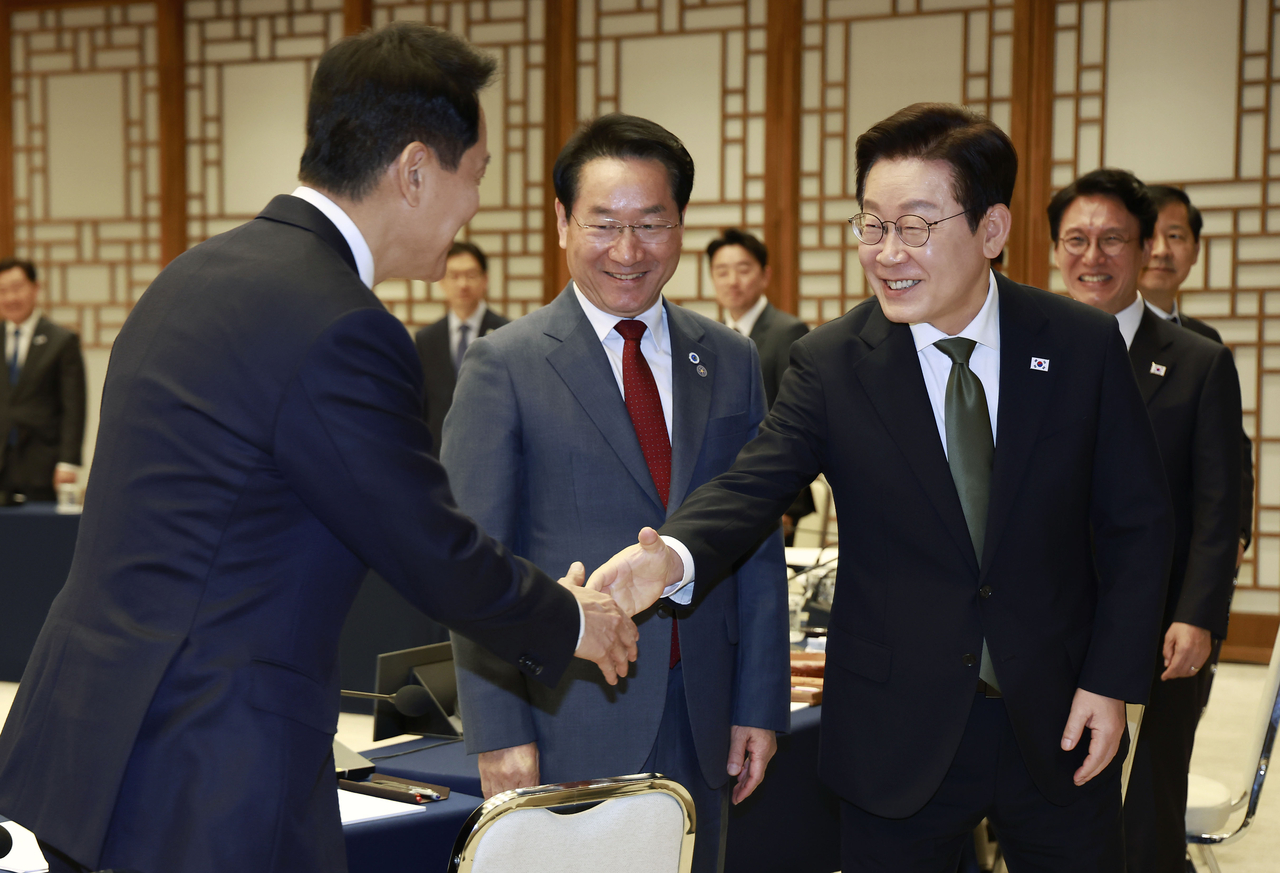President Lee Jae Myung (right) shakes hands with Seoul Mayor Oh Se-hoon (left) at a meeting between the president and leaders of local governments at the presidential office in Seoul on Wednesday. (Pool photo via Yonhap)