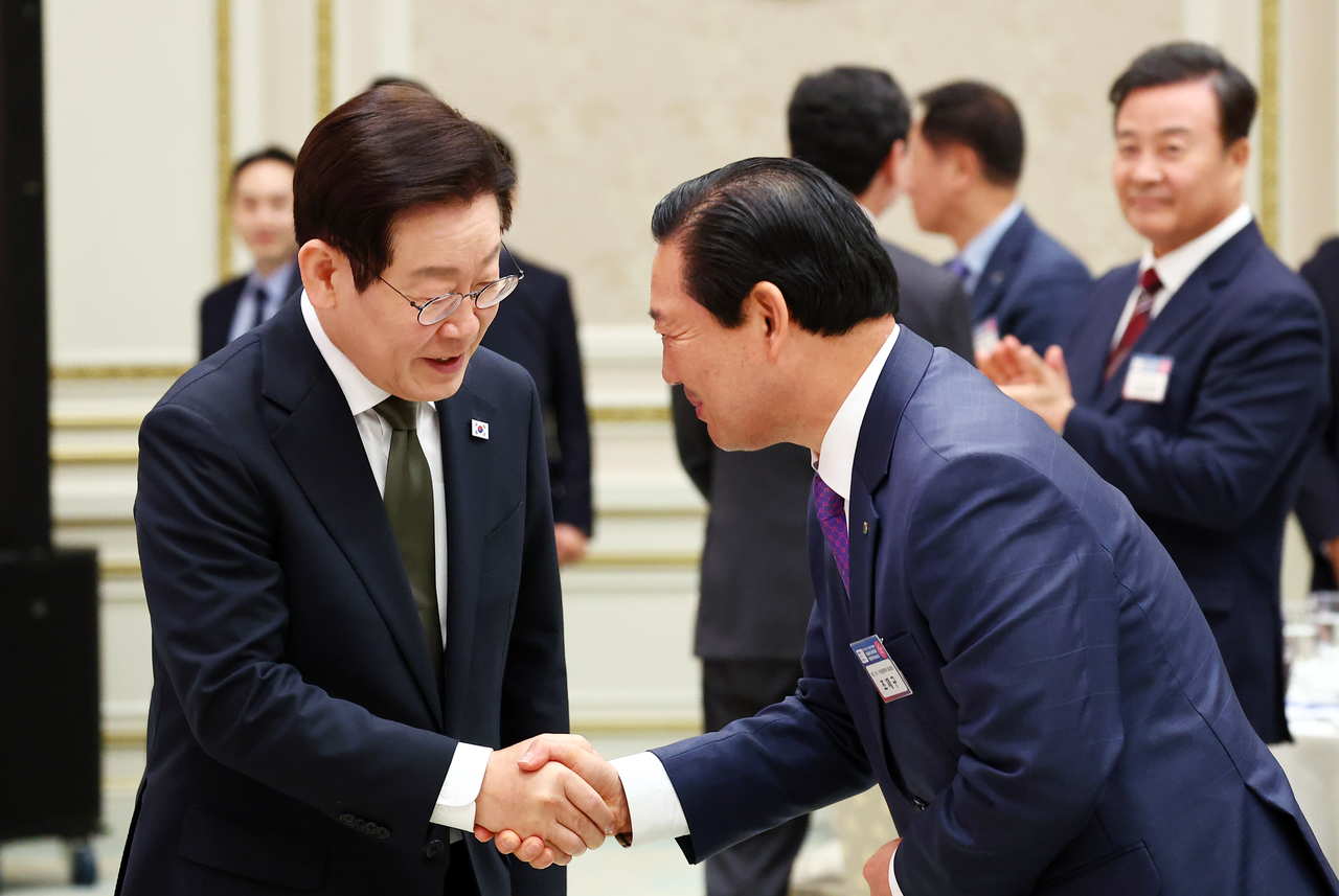 President Lee Jae Myung (left) shakes hands with Cho Jae-gu, head of Daegu's Nam-gu Office, during a luncheon with leaders of local governments at Cheong Wa Dae in Seoul on Wednesday. (Yonhap)