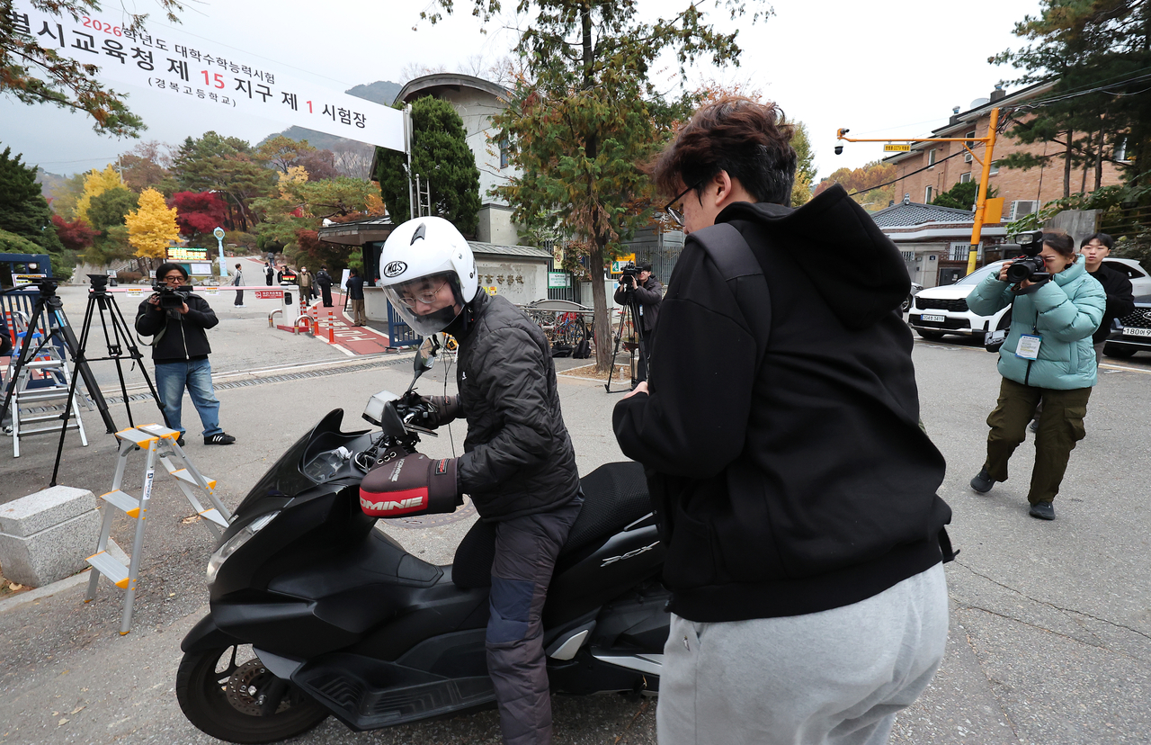 A student arrives on a motorcycle at an exam site set up at Gyeongbok High School in Jongno-gu, Seoul, on Thursday, the day of the 2026 College Scholastic Ability Test. (Yonhap)