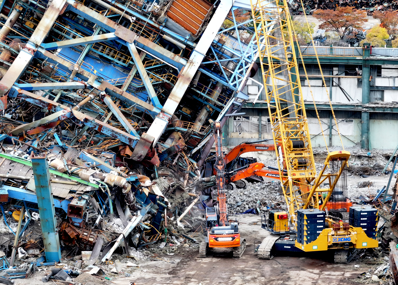 Construction vehicles move debris to clear a path for the search for missing workers under a collapsed boiler tower at a thermal power plant in the southeastern city of Ulsan on Wednesday. (Yonhap)