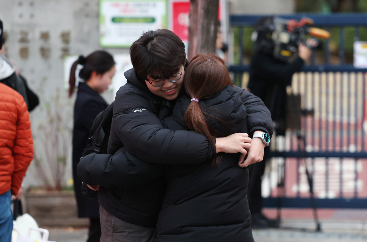 A student taking the 2026 CSAT hugs their mother in front of the test center set up at Kyungbock High School in Jongno-gu, central Seoul, on Thursday. (Yonhap)