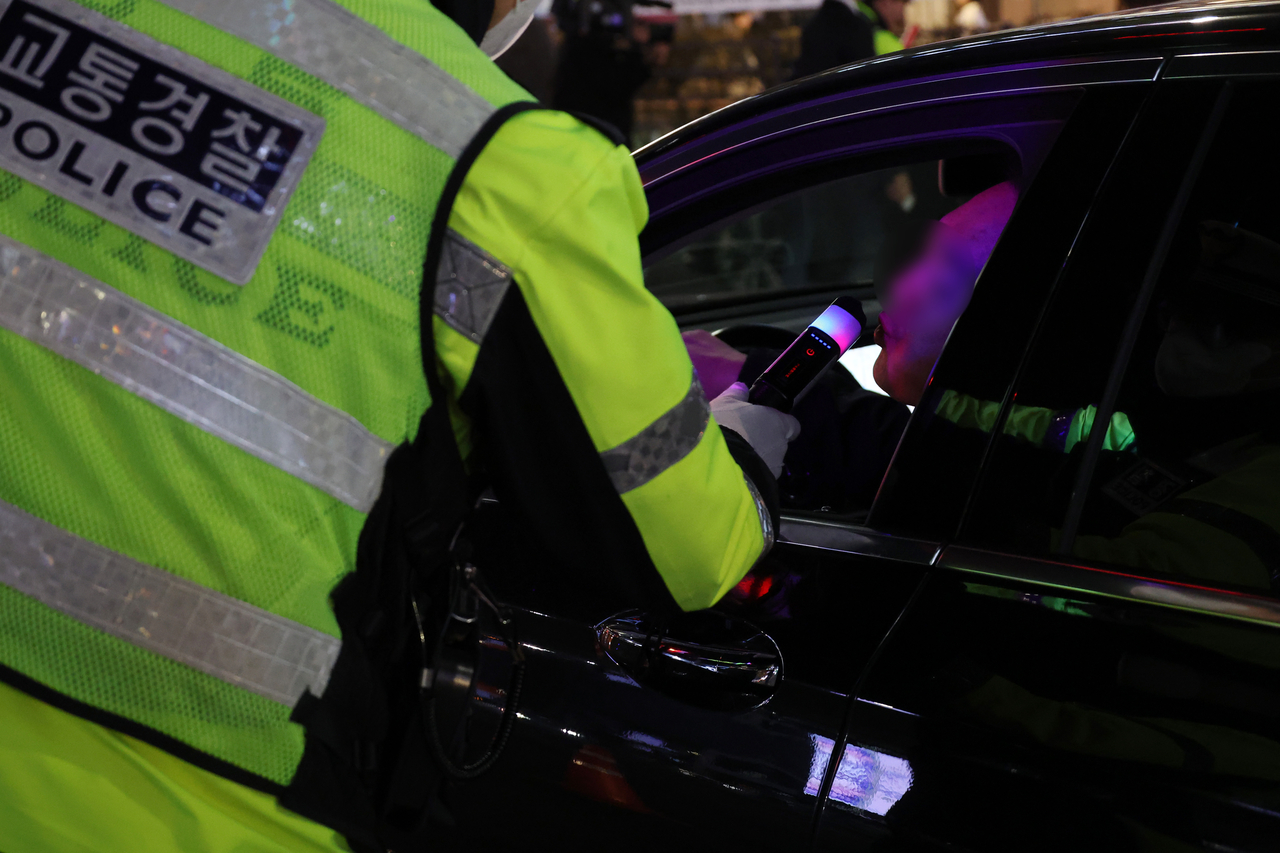 A police officer performs a breathalyzer test on Friday. (Yonhap)