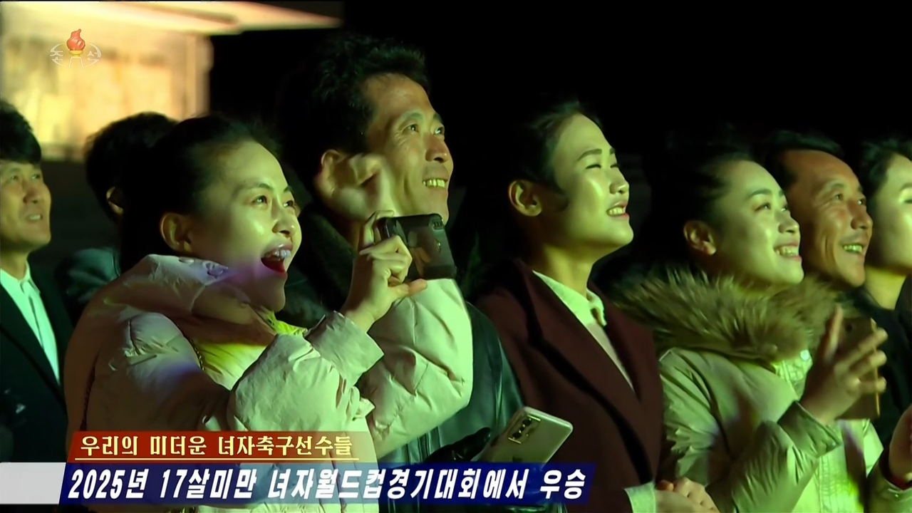 This screenshot from the Korean Central Television's Tuesday broadcast shows North Koreans celebrating in front of a large outdoor screen as the country's national Under-17 women's football team scores against the Netherlands during the World Cup finals. (Yonhap)