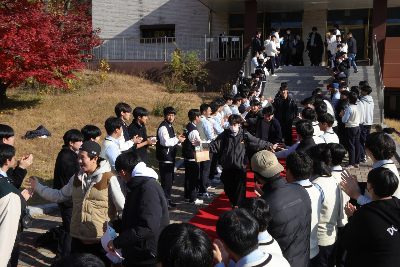 Youngseok High School in Uijeongbu, Gyeonggi Province, high-fives their juniors as they walk down the red carpet. Family members, teachers and students stand along the sidelines to show support and wish the test-takers good luck. (Yonhap)