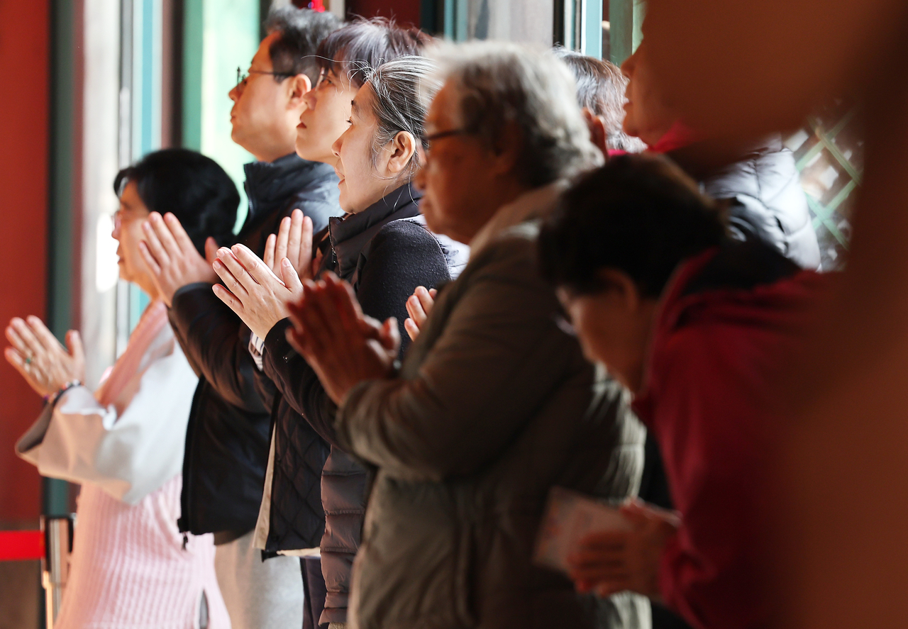 Family members of 2026 Suneung test-takers pray at a temple in Jongno-gu, Seoul, on Thursday. (Yonhap)