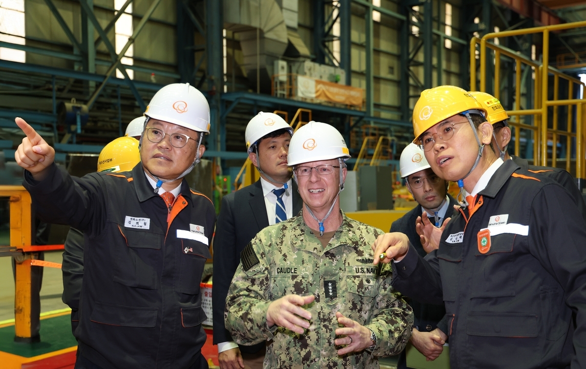 Hanwha Ocean CEO Kim Hee-cheol (left) briefs US Chief of Naval Operations Adm. Daryl Caudle (center, front) on the company's shipbuilding capabilities at a naval shipyard in Geoje, 390 km south of Seoul, on Saturday. (Yonhap)