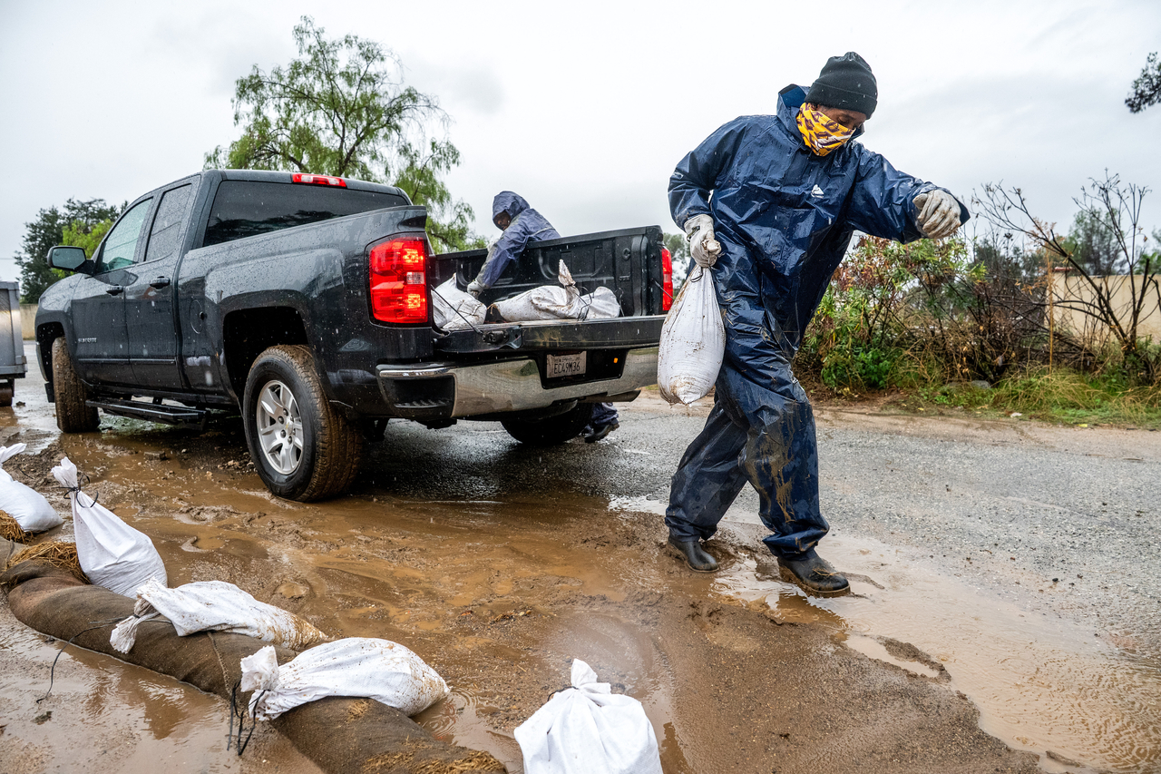 A person places a sandbag to prevent water from running off a property in Altadena, California, Saturday. (AP-Yonhap)