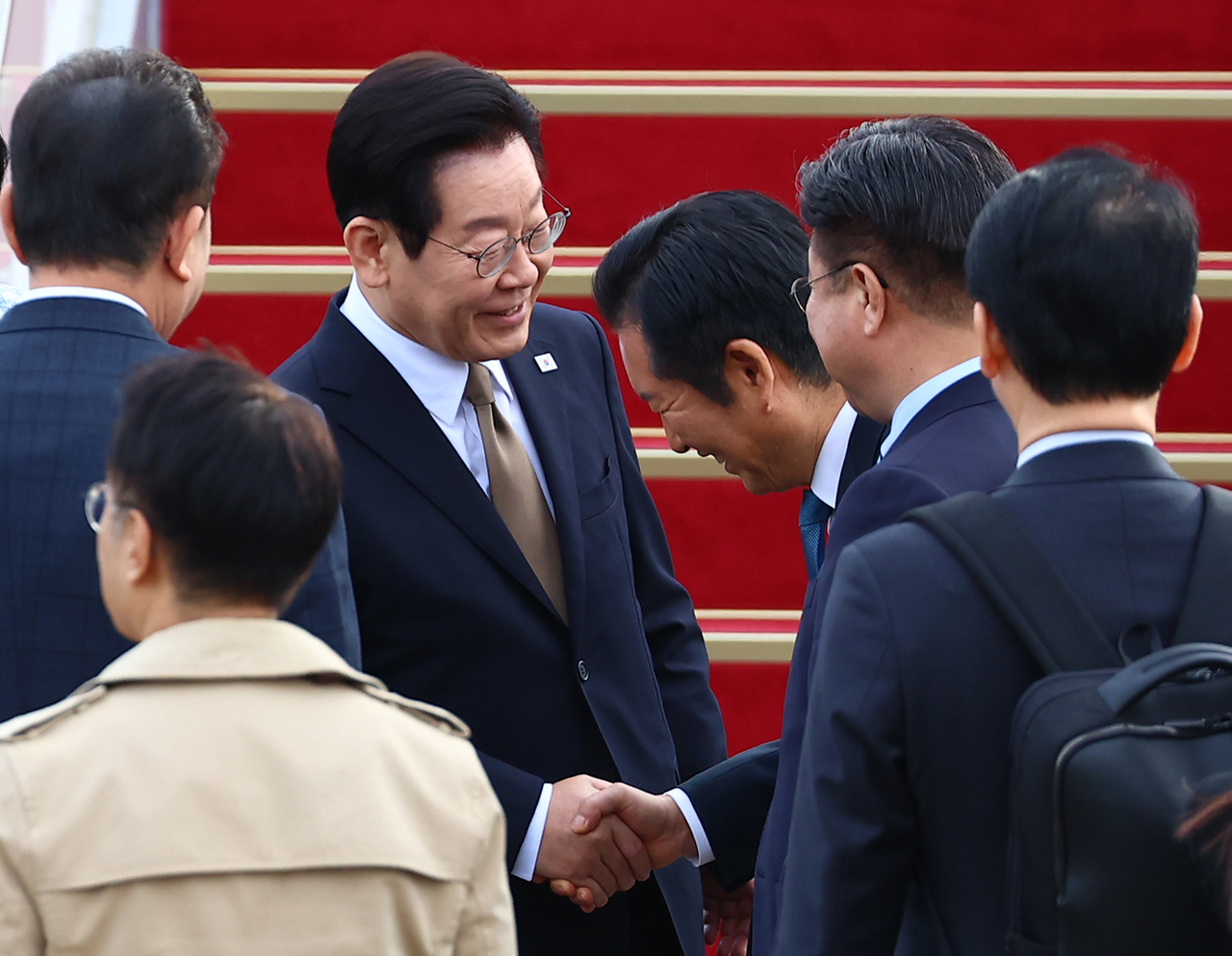 President Lee Jae Myung (fourth from right) shakes hands with Democratic Party of Korea Chair Rep. Jung Chung-rae (third from right) before boarding Air Force One at Seoul Air Base in Seongnam, Gyeonggi Province, Monday. (Yonhap)