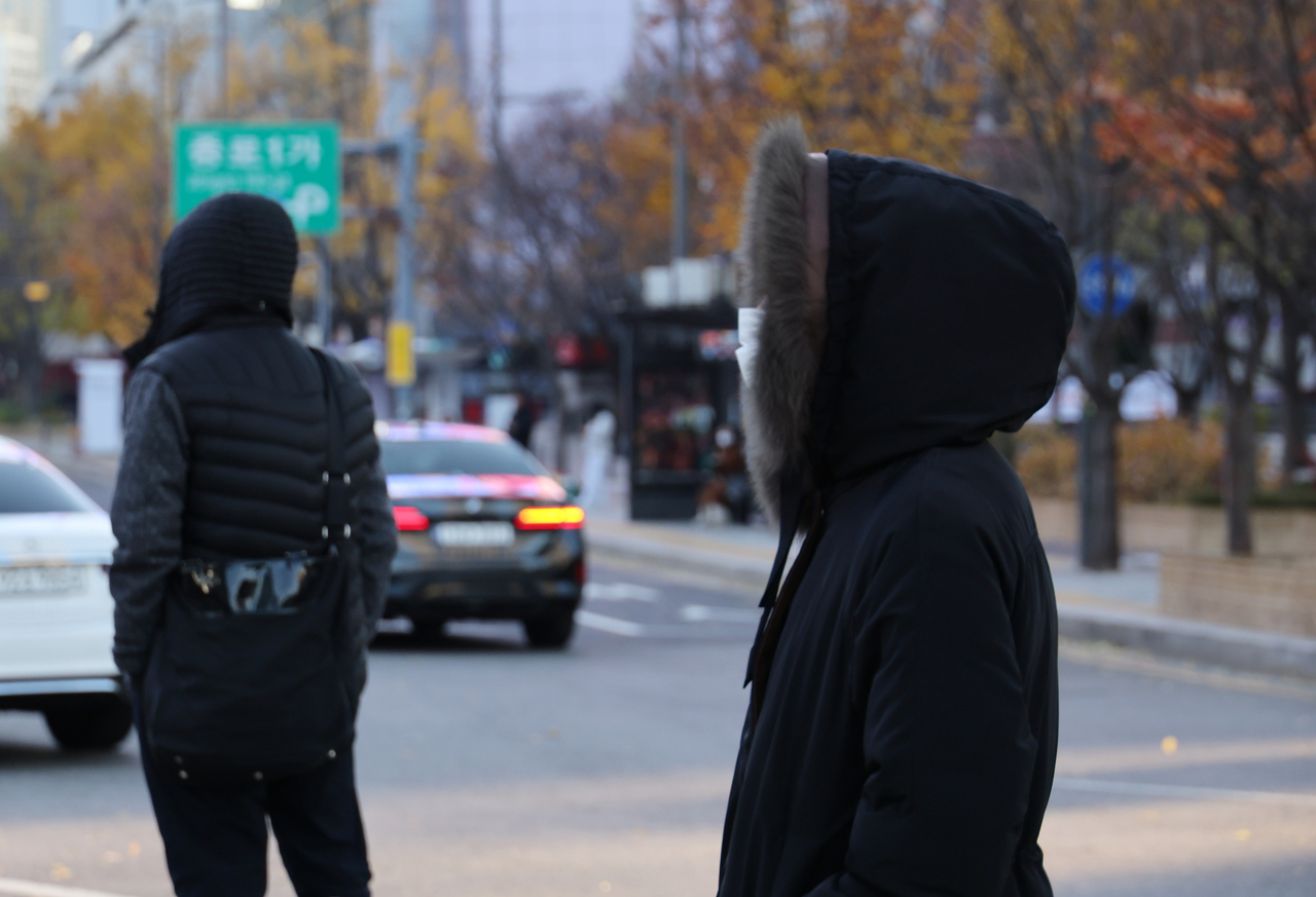 People walk quickly in Seoul’s Gwanghwamun area on Tuesday as the morning temperature in the capital falls below zero for the first time this autumn amid a cold snap. (Yonhap)