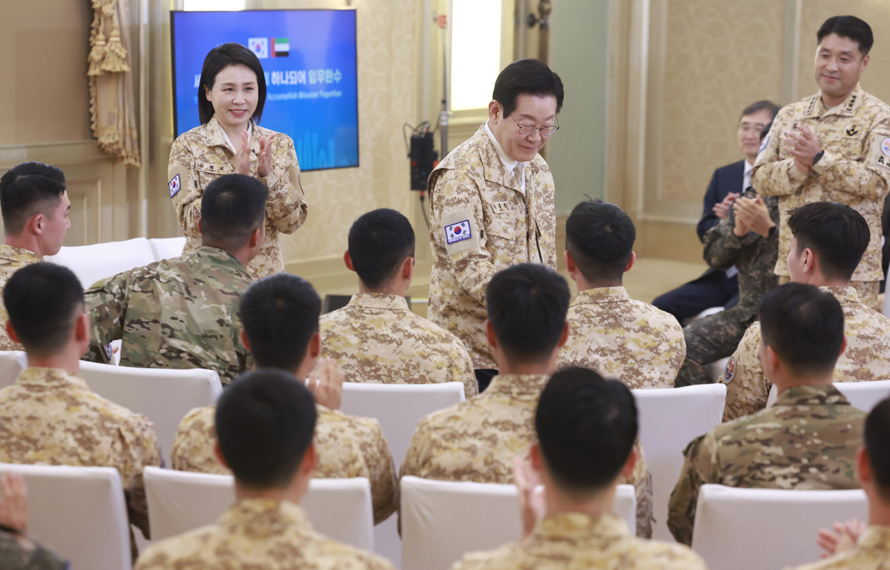President Lee Jae Myung (second from left) shakes hands with a member of the South Korean military contingent in the United Arab Emirates, Wednesday. (Yonhap)
