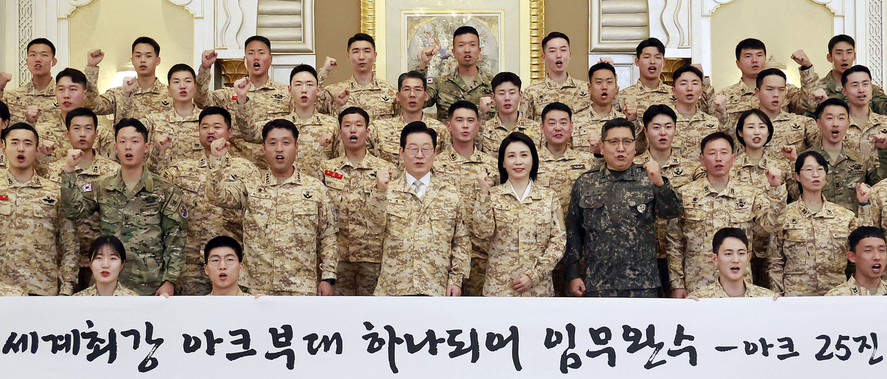 President Lee Jae Myung (seventh from left) and first lady Kim Hea Kyung (eighth from left) pose for a photo with the South Korean military contingent in the United Arab Emirates, Wednesday. (Yonhap)