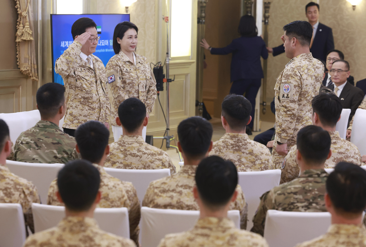 President Lee Jae Myung (left) receives a salute from a member of the South Korean military contingent in the United Arab Emirates, Wednesday. (Yonhap)