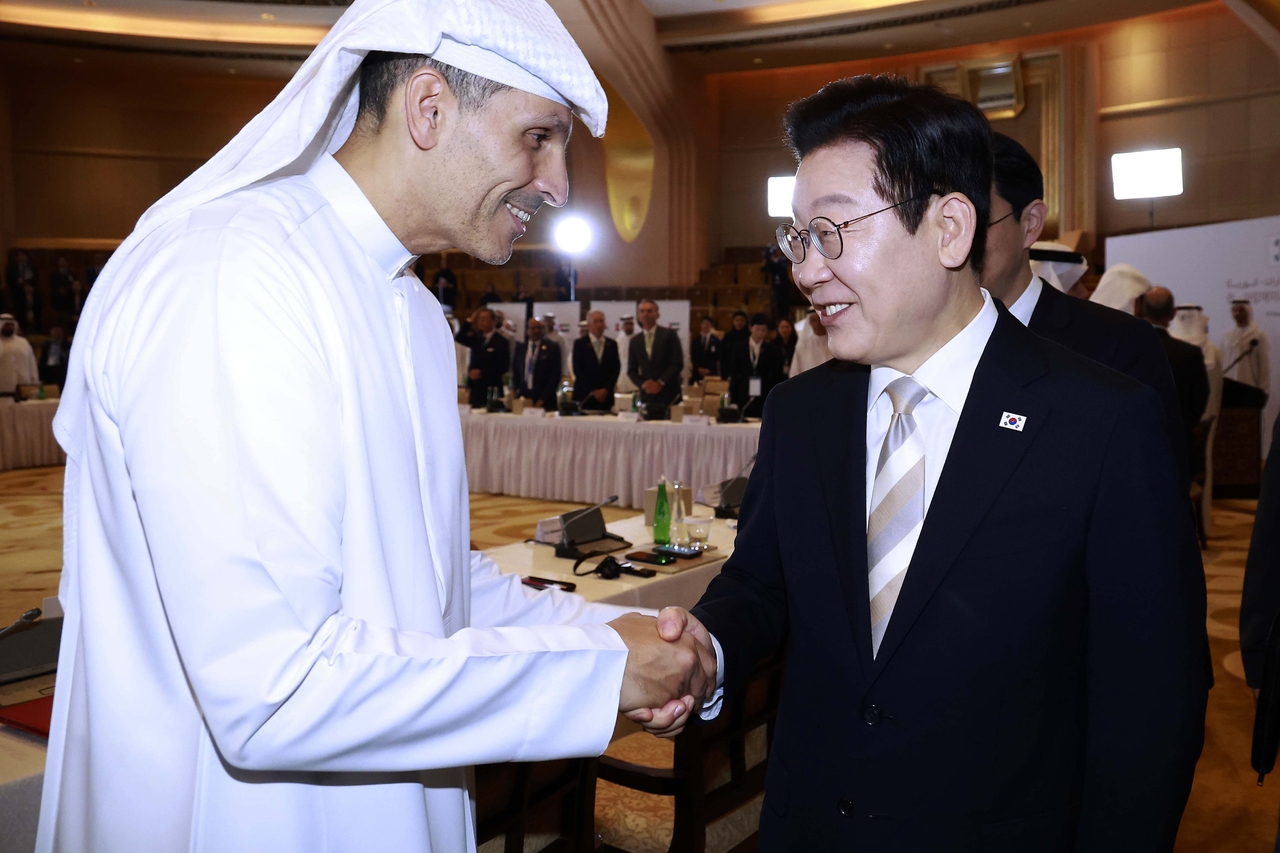 President Lee Jae Myung (right) shakes hands with Khaldoon Khalifa Al Mubarak, chair of the Abu Dhabi Executive Affairs Authority, during a business roundtable between South Korea and the United Arab Emirates, in Abu Dhabi on Wednesday. (Yonhap)