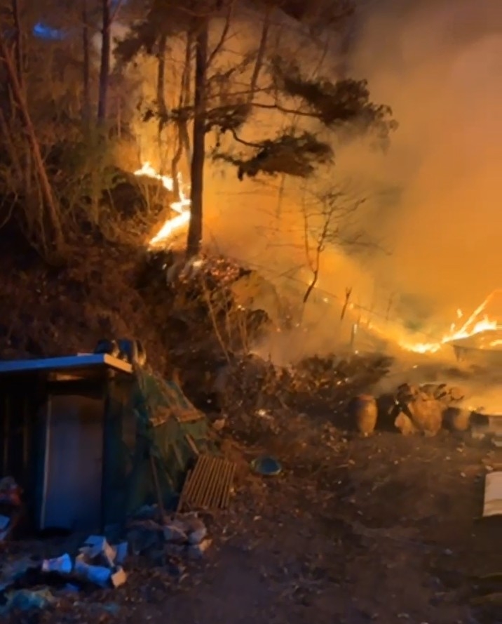 A fire burns after apparently breaking out from a farm container in Girin-myeon, Inje County, Gangwon Province, on Thursday afternoon, spreading to a nearby mountainside, with firefighters and forestry authorities continuing suppression efforts. (Gangwon Province Fire Department)
