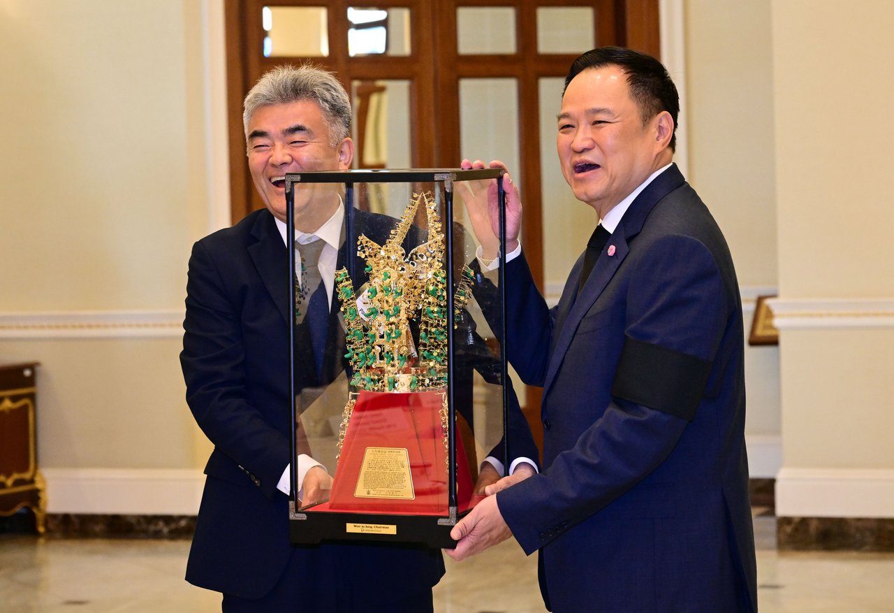 Jung Won-ju (left), chairman of Daewoo E&C and Herald Media Group, and Thai Prime Minister Anutin Charnvirakul hold a gold crown replica for a photo during the meeting at the Government House of Thailand in Bangkok on Tuesday. (Park Hae-mook/The Korea Herald)