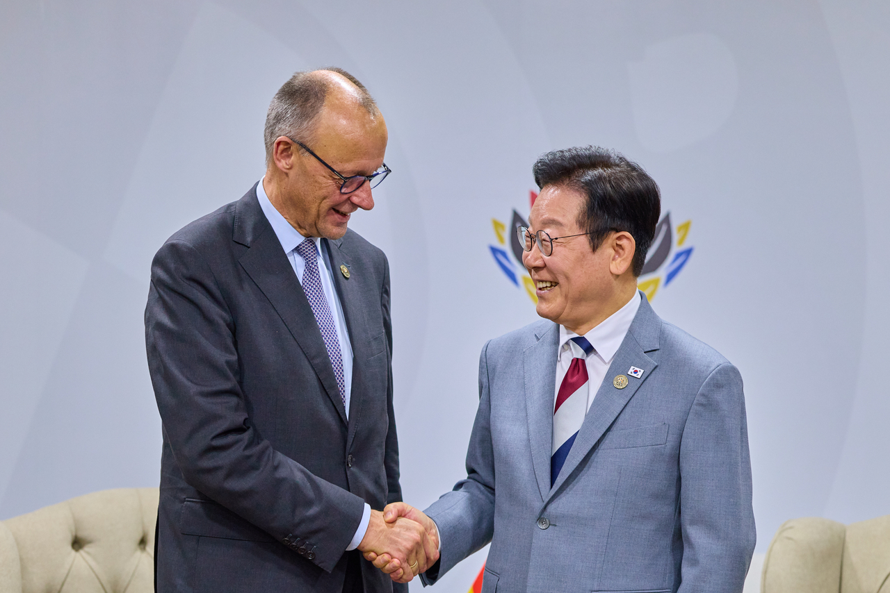 President Lee Jae Myung (R) shakes hands with German Chancellor Friedrich Merz during their summit held on the sidelines of the Group of 20 summit in Johannesburg, South Africa on Saturday. (Yonhap)