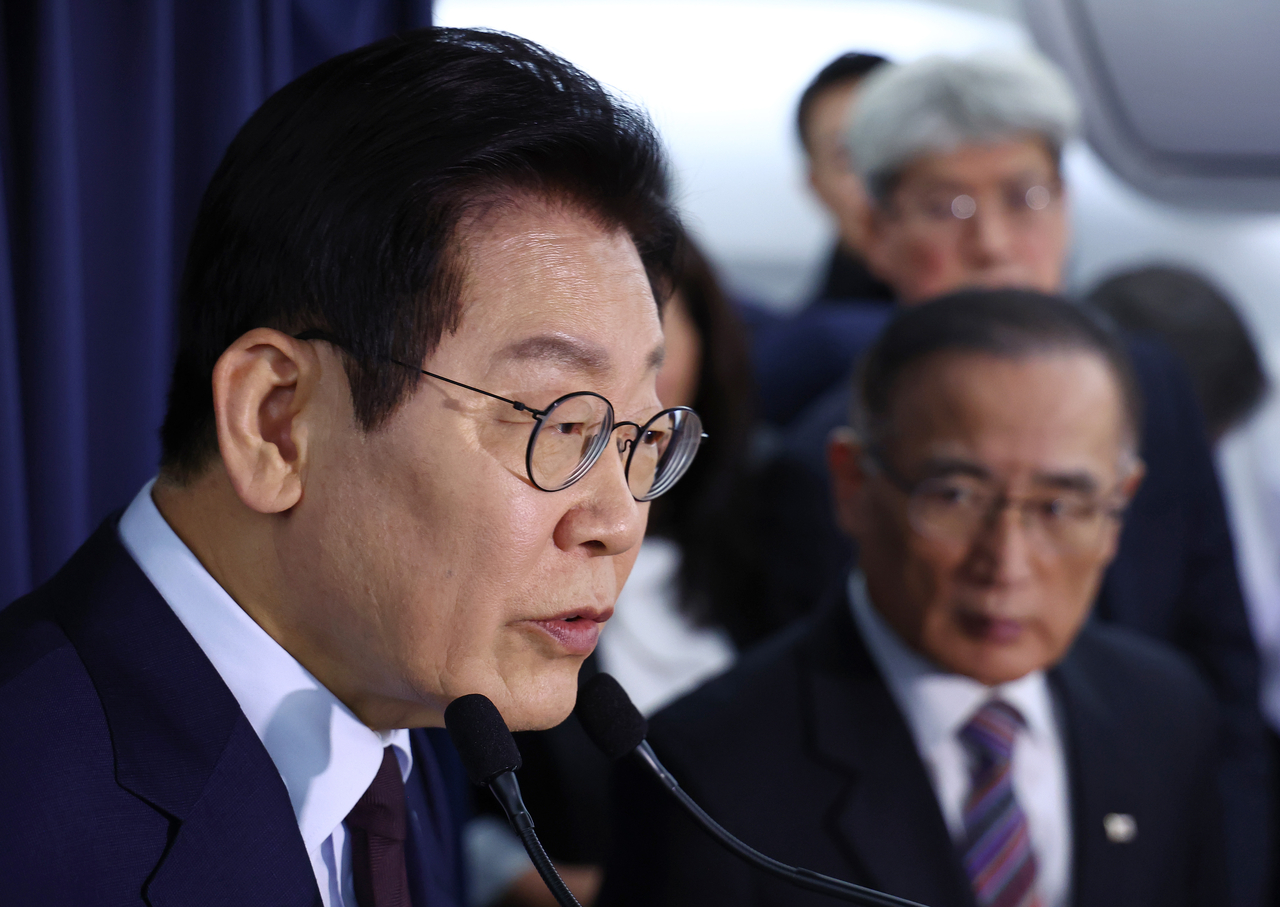 President Lee Jae Myung (left) speaks during a press conference aboard the presidential plane before arriving in Turkey for a state visit on Monday. (Yonhap)