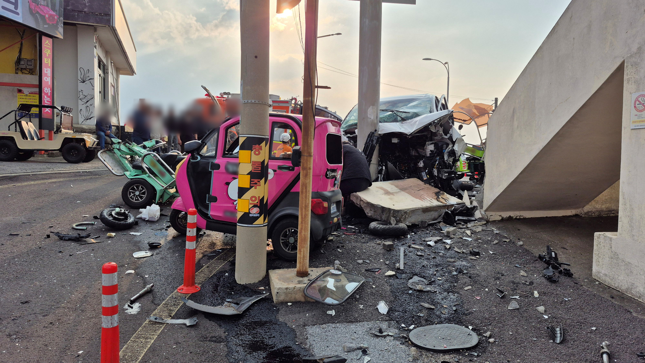 A white van, along with unrelated colorful rental vehicles for tourists, is seen crashed near a road sign next to Cheonjin Port on the small island of Udo, near Jeju Island, Monday. (Yonhap)