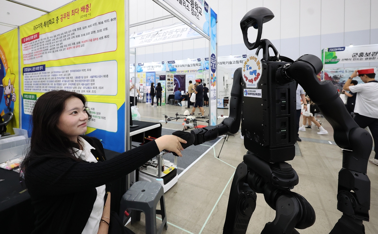 A student shakes hands with a humanoid robot at the Daegu Technical High School booth during the Vocational Education Expo held at EXCO in Daegu in September. (Newsis)