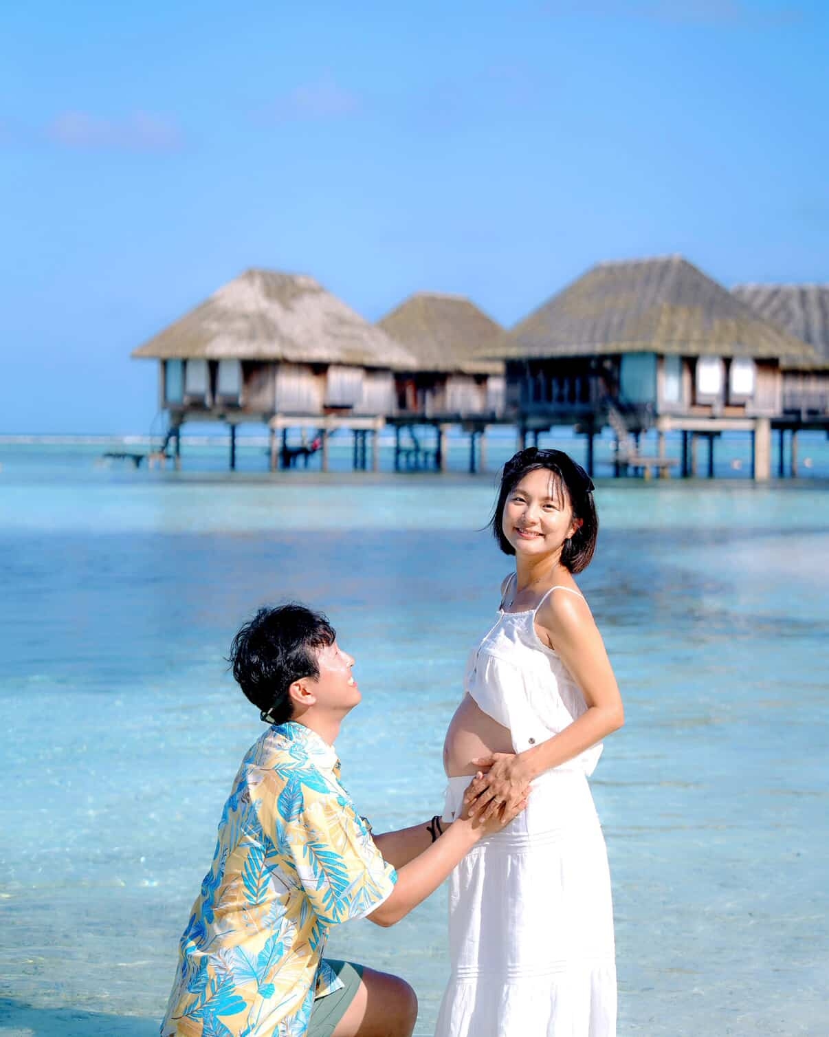 A photo shows Jin, at six months pregnant, posing with her husband on a Maldives beach during their babymoon. (Courtesy of Jin)
