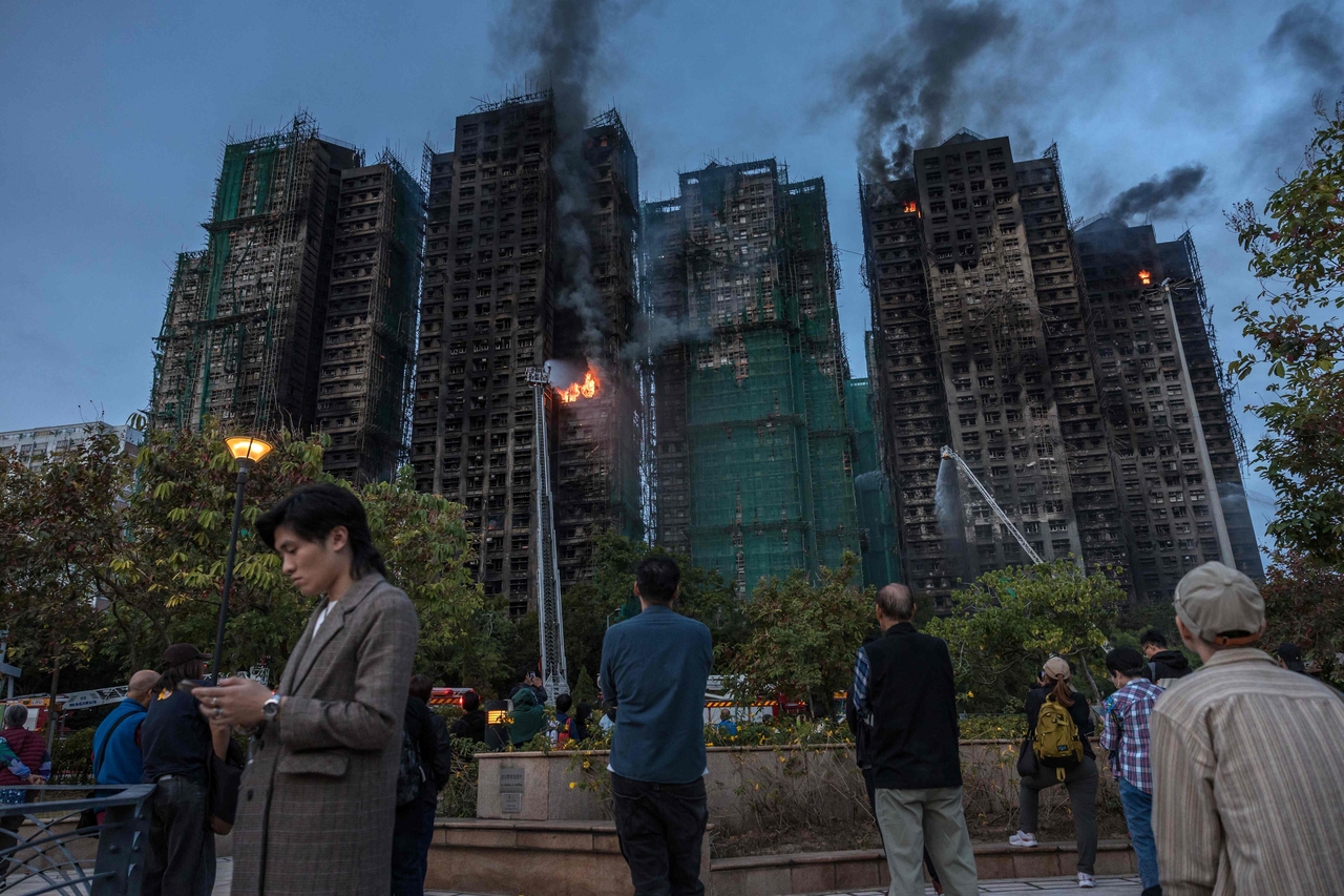 People watch as smoke rises from apartments after a major fire swept through several blocks at the Wang Fuk Court residential estate in Hong Kong's Tai Po district, Thursday. (AFP-Yonhap)