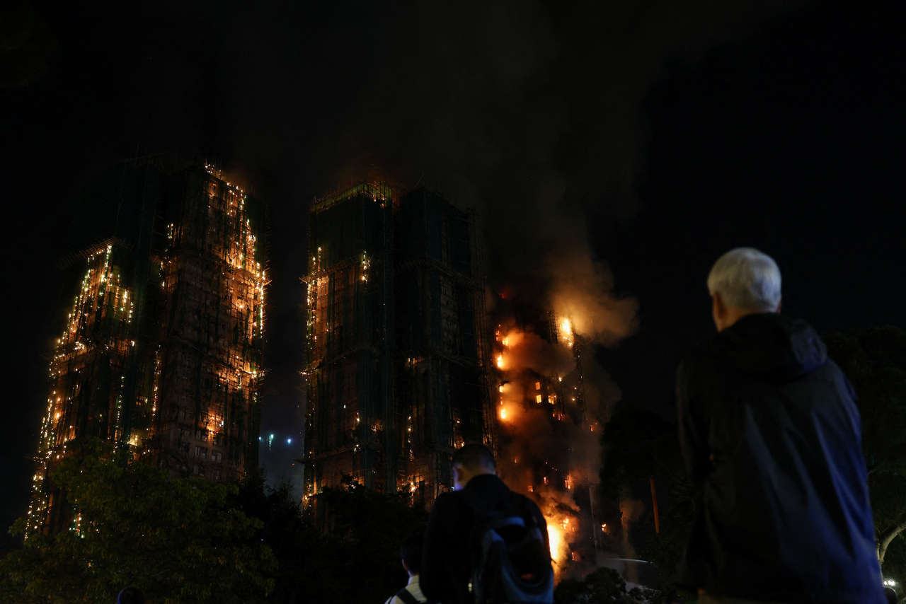 People watch as flames burn bamboo scaffolding across multiple buildings at Wang Fuk Court housing estate, in Tai Po, Hong Kong, China,Tuesday. (Reuters - Yonhap)