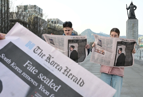 This file photo, taken Apr. 4, shows a foreign couple reads a Korea Herald extra edition at Gwanghwamun Square in Jongno-gu, central Seoul. (Herald)